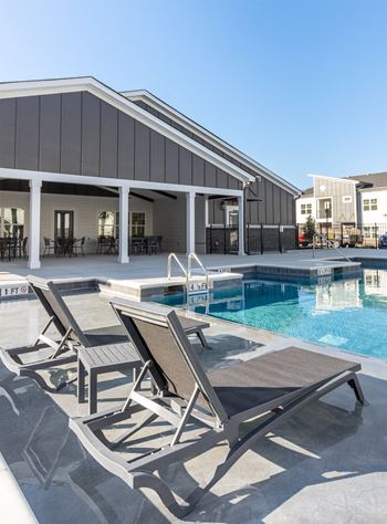 a pool and lounge chairs in front of a building